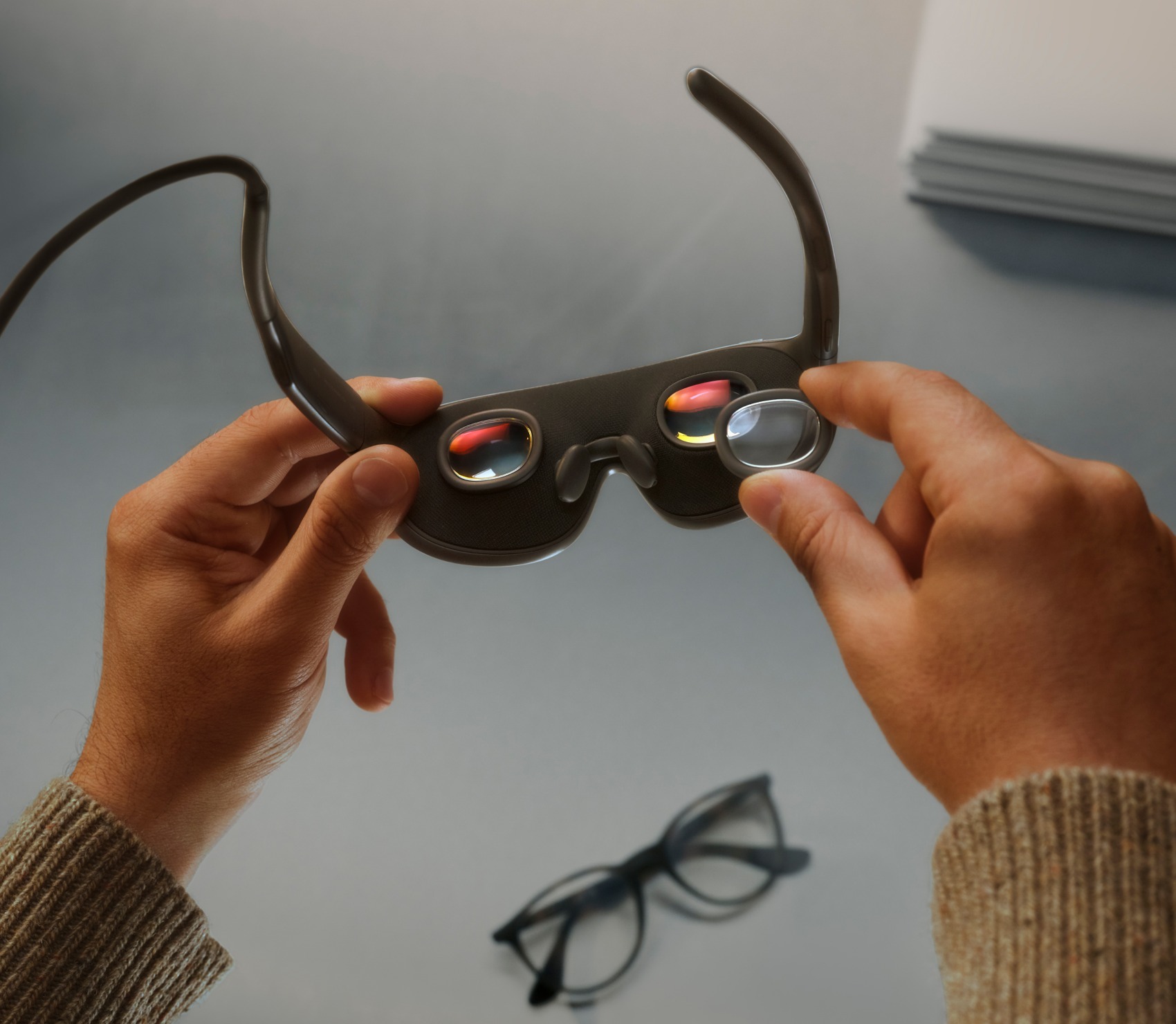 Una persona sostiene las Meta VR Glasses y ajusta la zona interior de sus lentes.